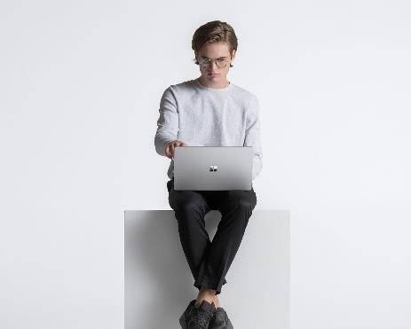 Un joven trabaja con una Surface Laptop Go en sus piernas