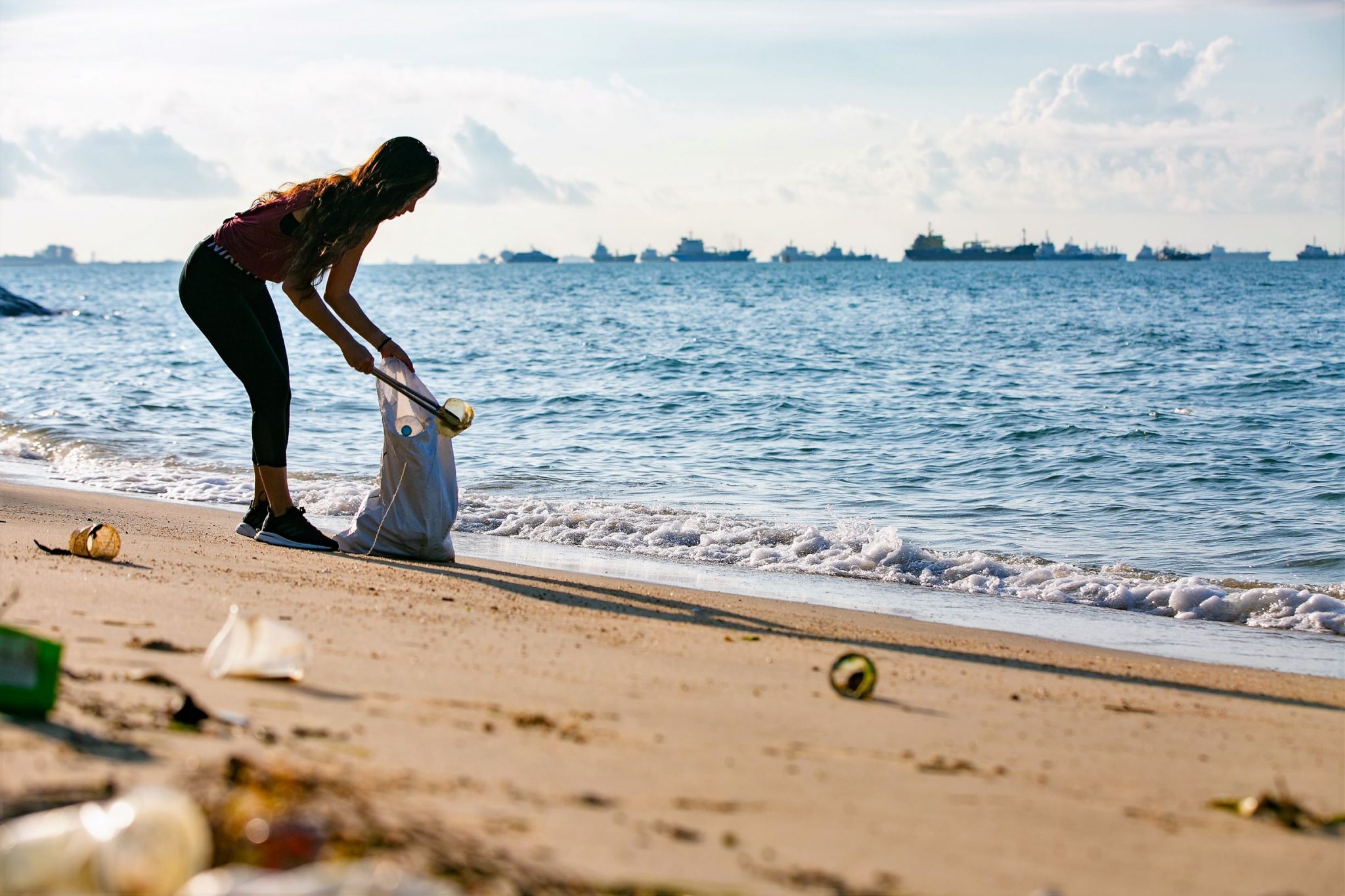 Mujer recolecta basura en una playa