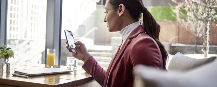 Mujer ejecutiva de pequeñas empresas en una mesa usa Microsoft Teams en un iPhone.