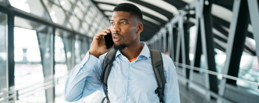 Un joven camina por un aeropuerto hablando por teléfono