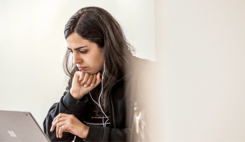 Una mujer con audífonos frente a una laptop