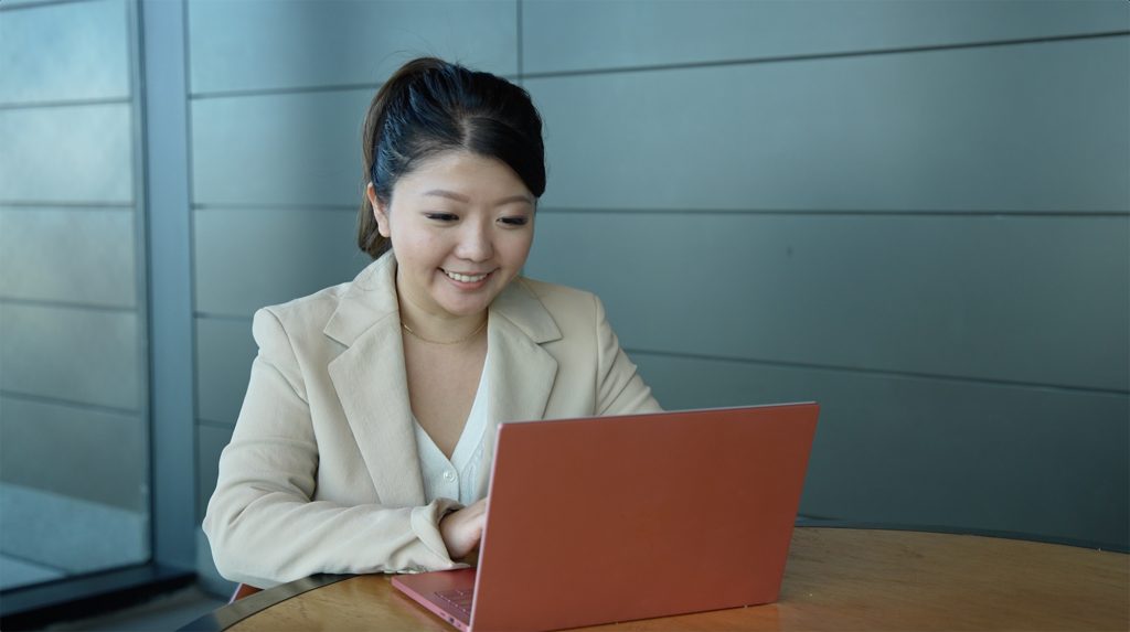 La mujer sonríe mientras mira su computadora portátil