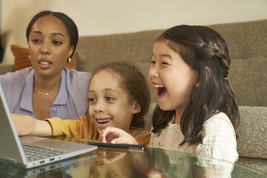 Mujer y dos niñas disfrutan lo que hay en su computadora portátil
