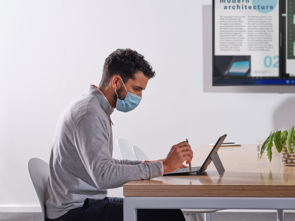 Hombre con una máscara trabaja en una computadora portátil
