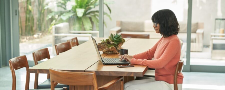 Mujer trabaja en la mesa del comedor en la computadora portátil.