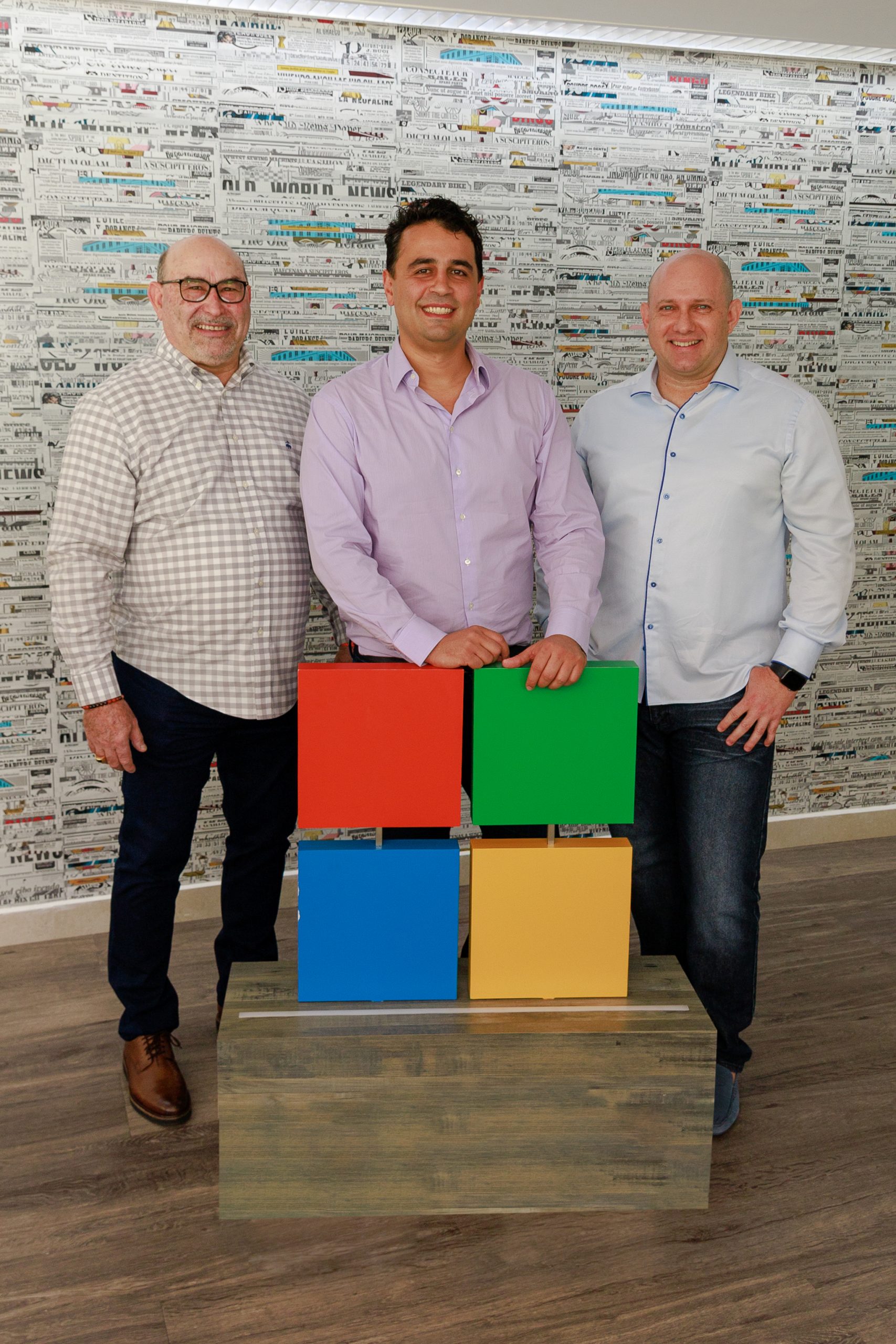 Tres hombres de pie detrás del logo de Microsoft