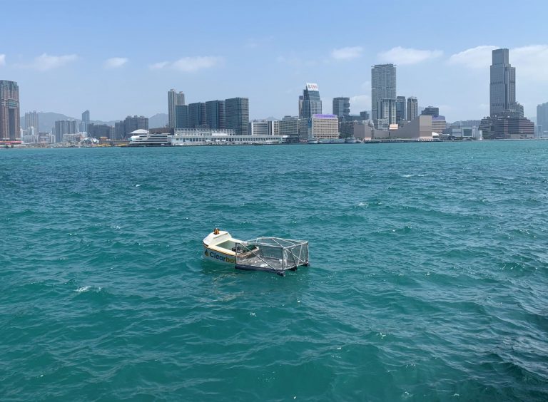Un pequeño bote en el agua con el horizonte de la ciudad al fondo.