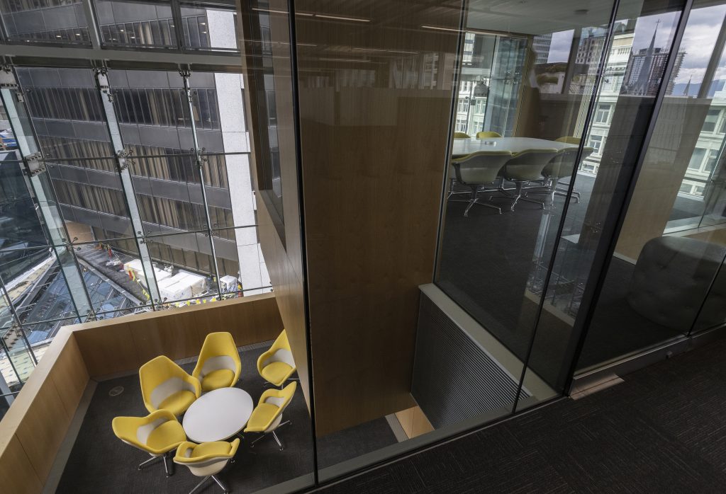 Foto tomada en la sede de TELUS en Vancouver, B.C., que muestra dos oficinas interiores con sillas agrupadas alrededor de mesas y vistas desde las ventanas.