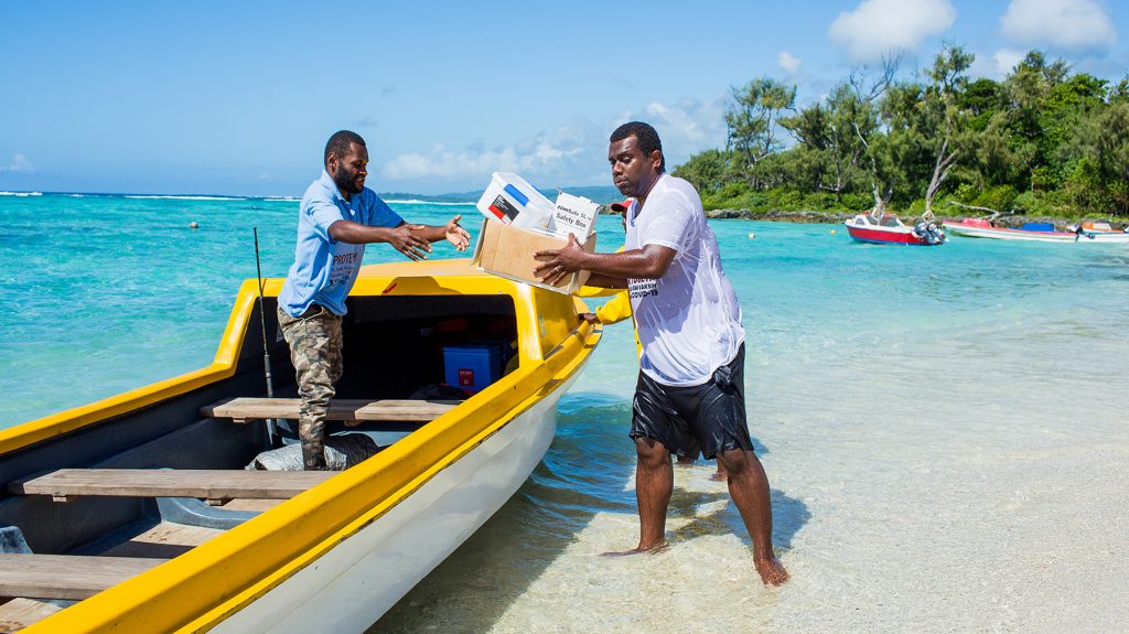 Trabajadores de la salud entregan vacunas contra el COVID-19 en un bote en la playa