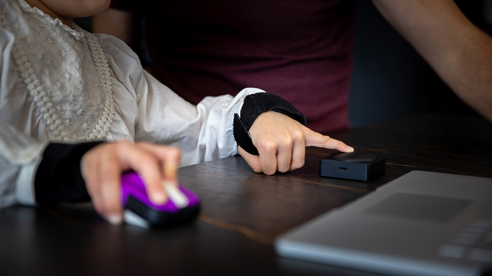 Una niña usa un Adaptive Mouse y un Adaptive Button.