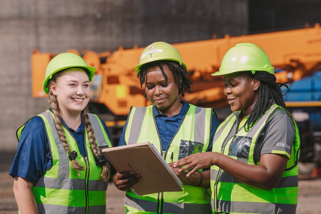 Women In Helmets And Vests Talk About Work