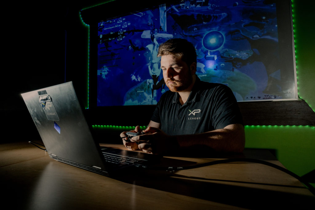 Nathanael Bateman, entrenador de XP League, monitorea la acción del juego en vivo en la pantalla de su computadora portátil.