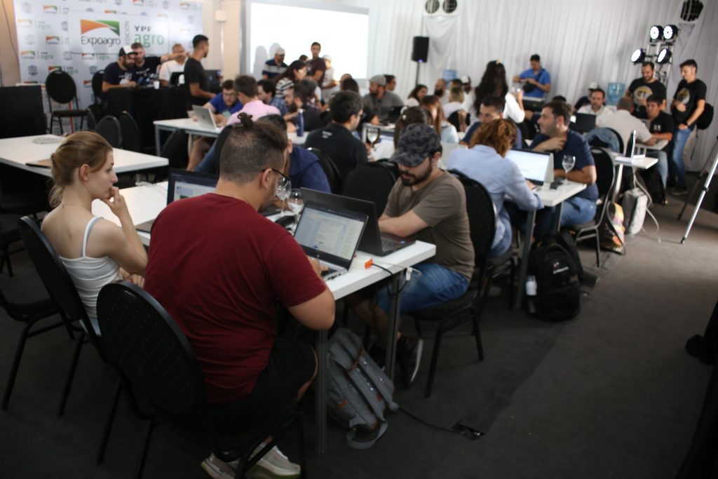 Personas sentadas en mesas, con laptops, en una conferencia