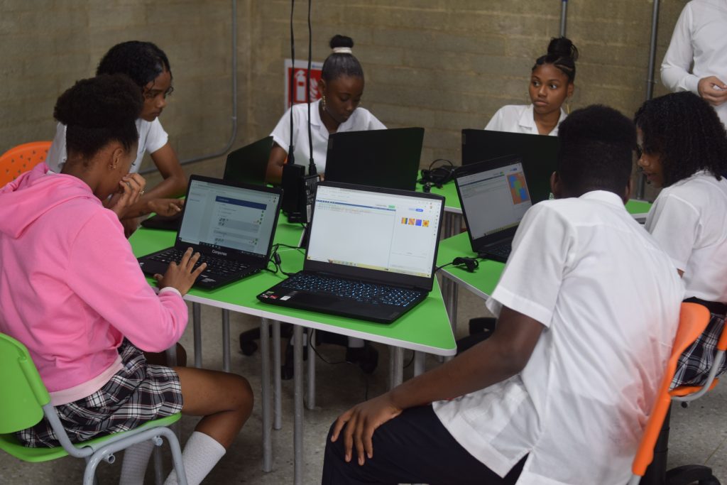 Jóvenes del programa TEALS en Colombia sentados en un escritorio con laptops