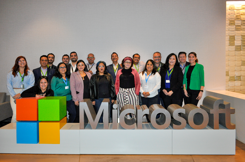 Un grupo de personas posa frente al logo de Microsoft