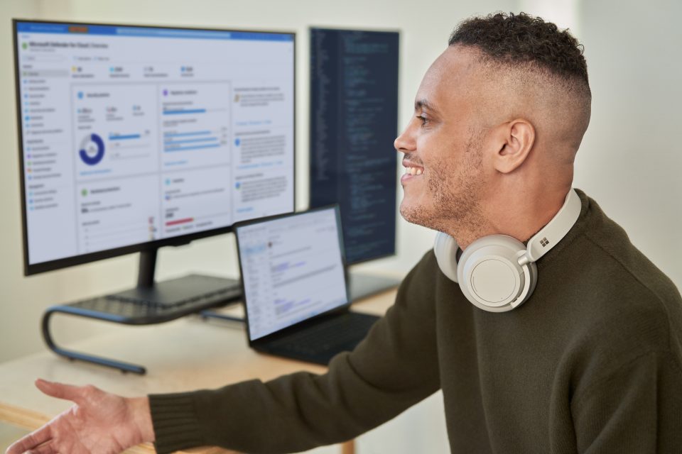 Un hombre con Surface Headphones trabaja con diferentes monitores