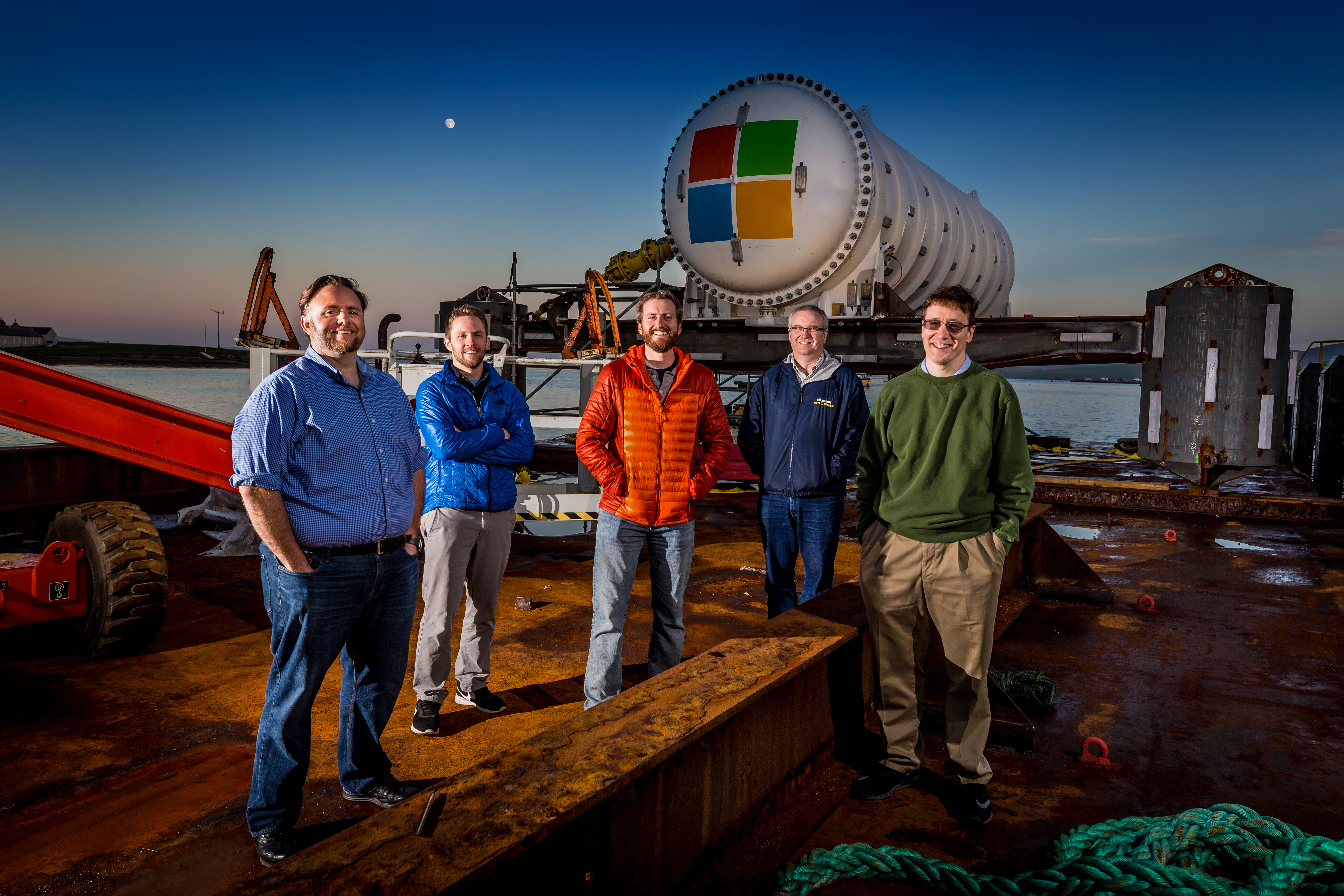 Fünf Mitarbeiter mit dem Microsoft Unterwasser-Rechenzentrum welches gerade ins Wasser gelassen wird