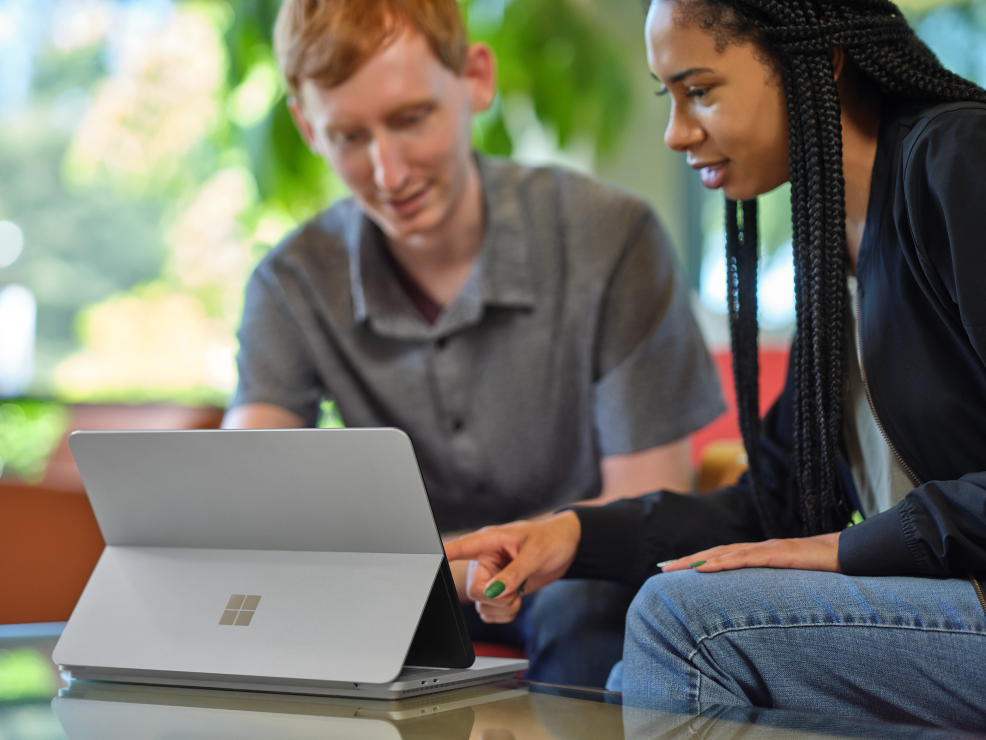 Two people looking at the screen of a Microsoft Surface laptop and learning about the Microsoft for Startups program