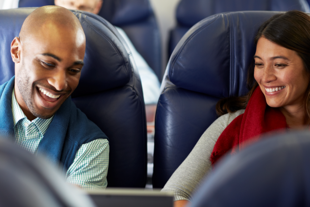 homem e mulher sentados no banco de avião sorrindo