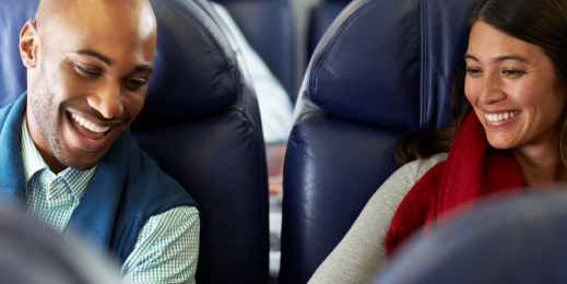 homem e mulher sentados no banco de avião sorrindo