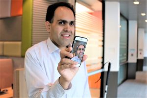 Saquib Shaihk holds up his smartphone with the Seeing Ai app activated.