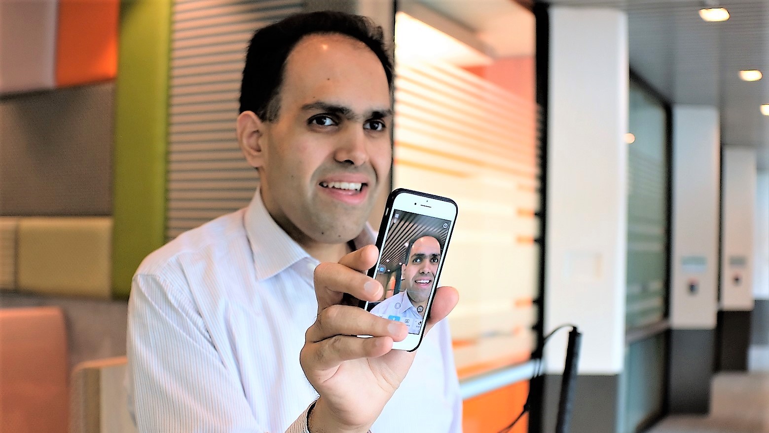 Saquib Shaihk holds up his smartphone with the Seeing Ai app activated.