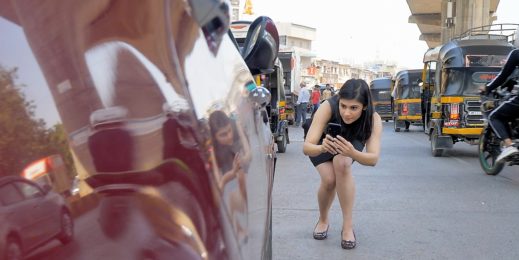Woman takes a smartphone image of her damaged car on a busy street