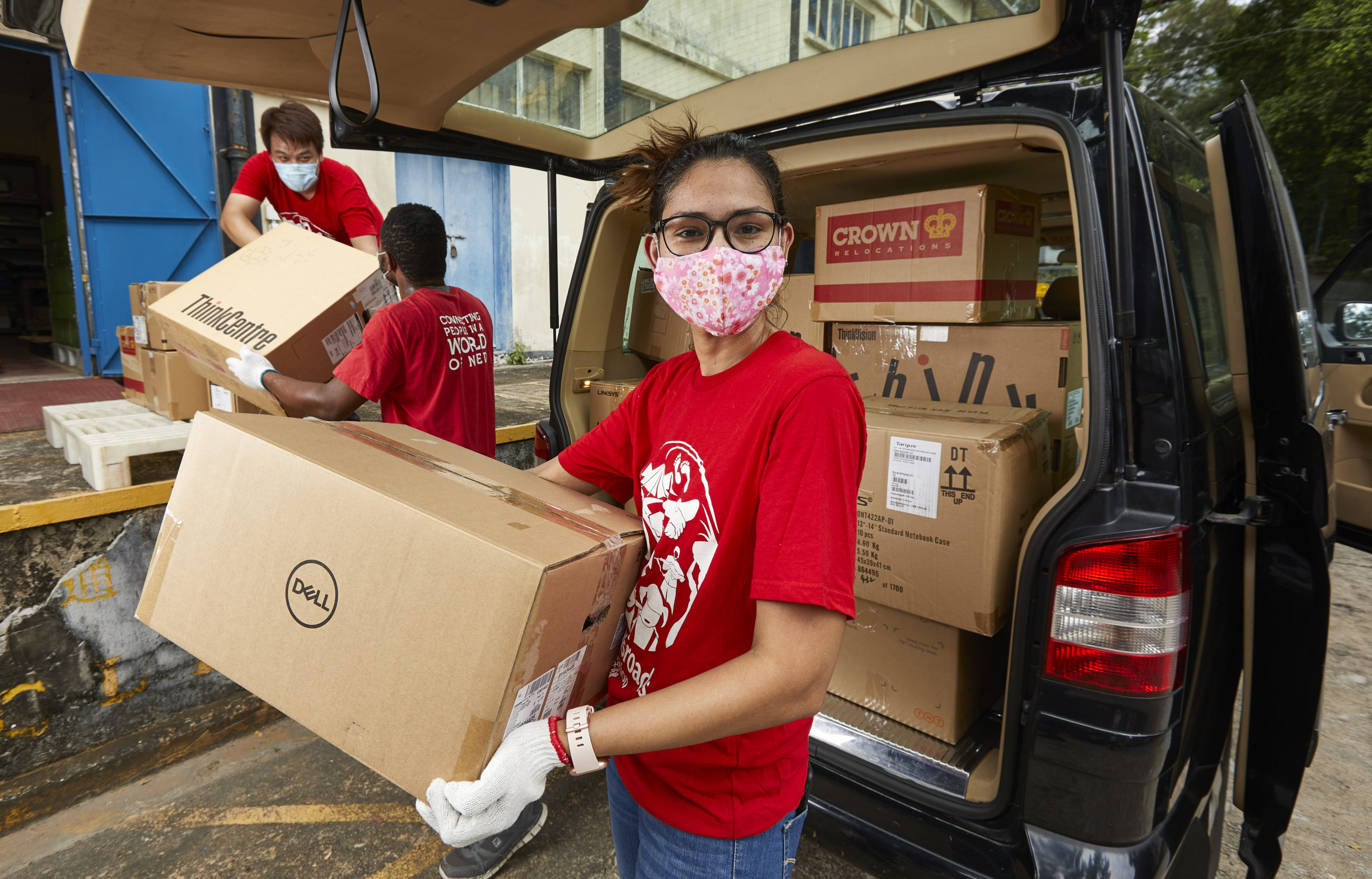 A woman wearing a face mask moves a box from the back of a van.