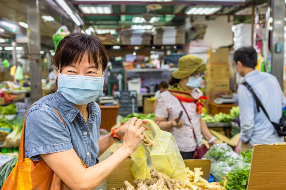 A woman wears a mask at a vegetable market