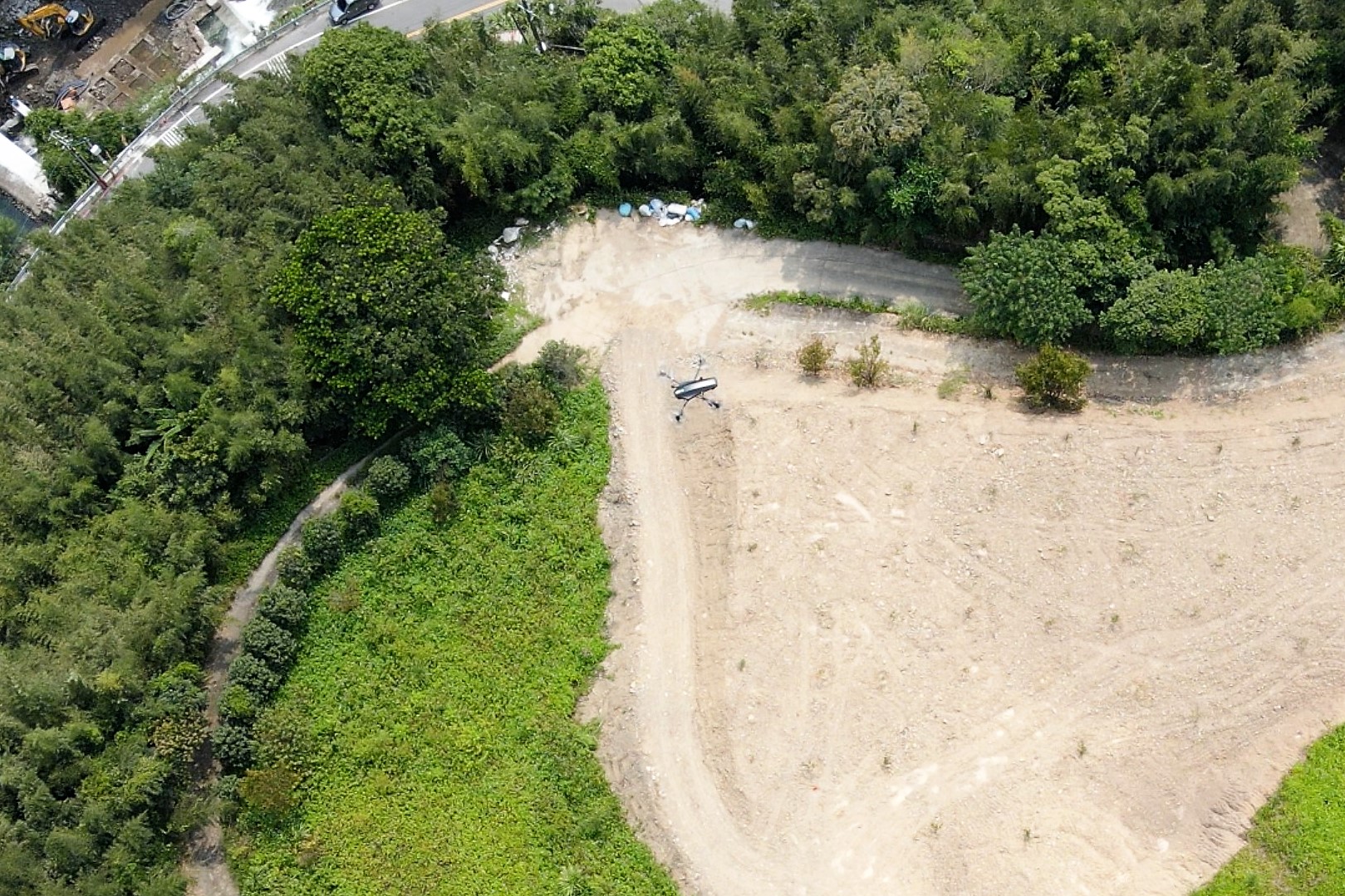 A drone flies over cleared land.