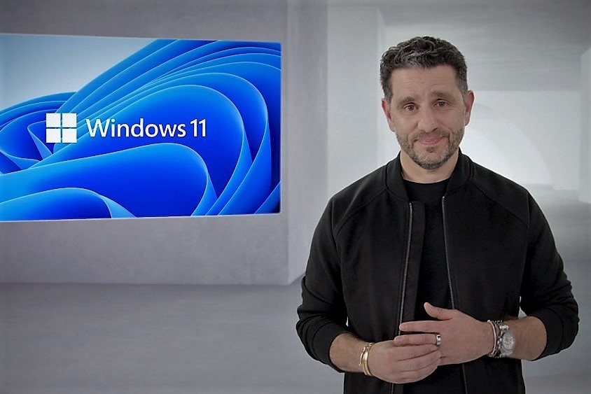 A man stands in front of a Windows 11 logo