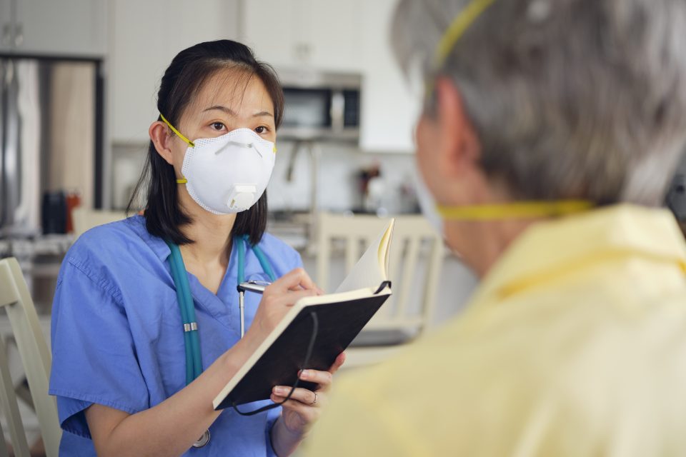 A healthcare worker attend to a senior, both are wearing masks