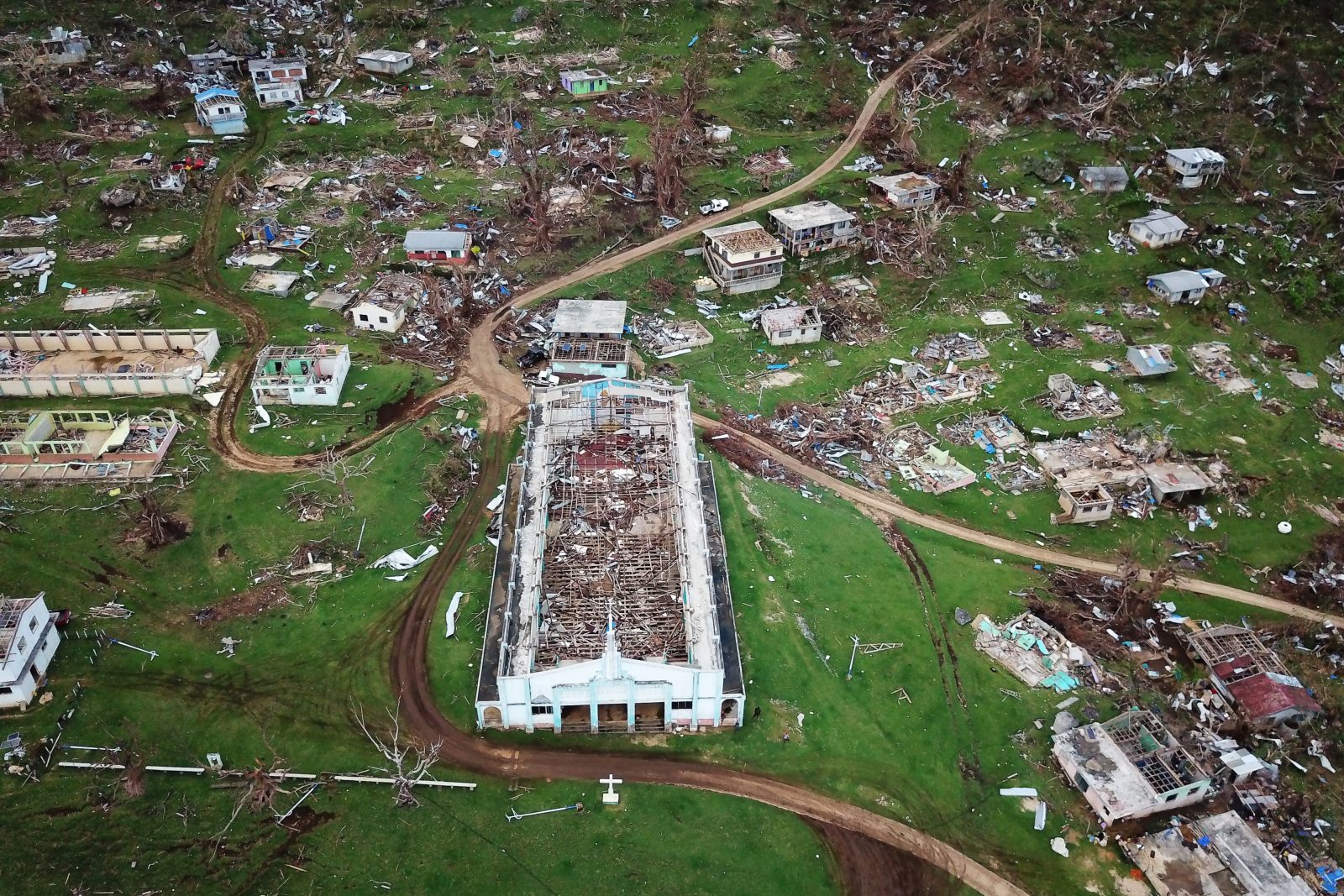 An aerial photograph over a Pacific island village that has been devastated by a tropical cyclone.