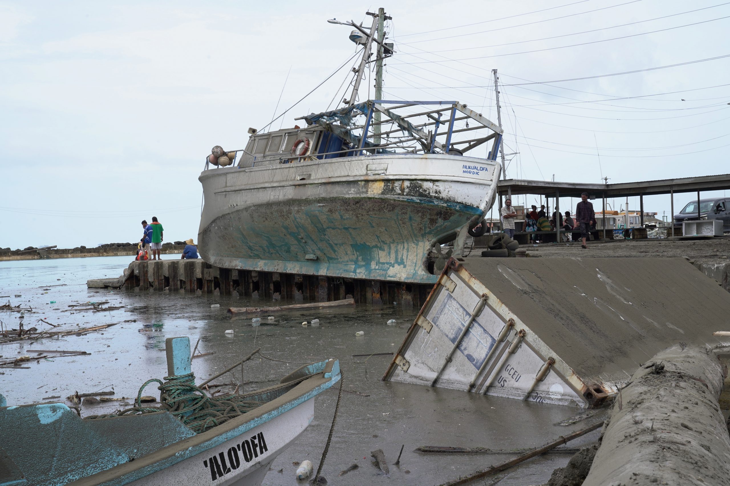 A large boat lies out of the water and near a pier after a tsunami hit.