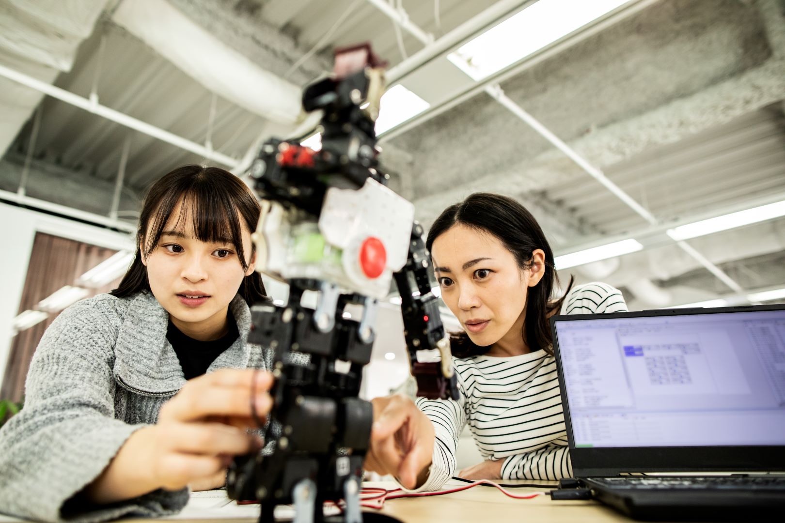 Two women working on a robotic device