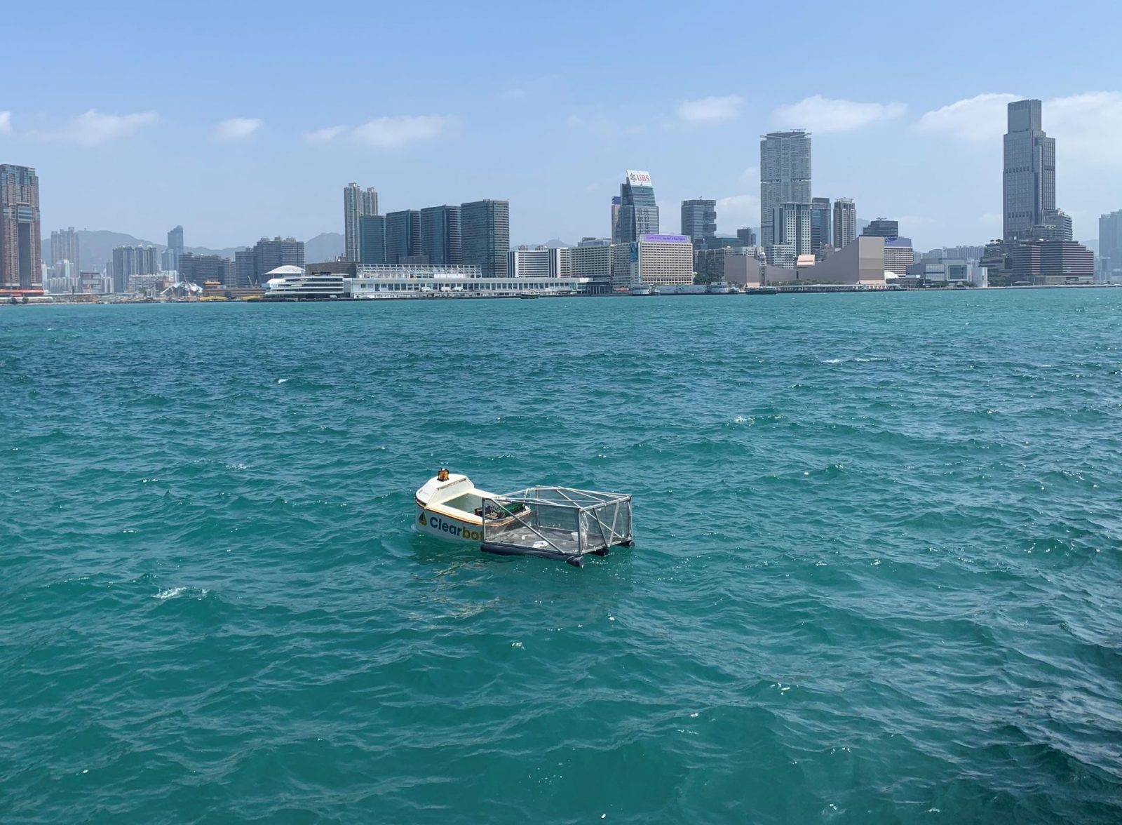 A small boat on the water with a city skyline in the background.