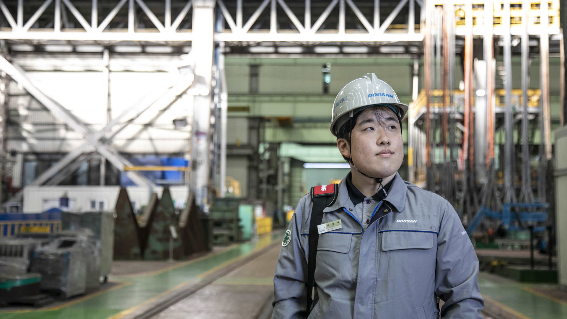 A man stands in front of a factory floor