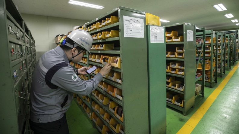 A man looks at parts in a storage room