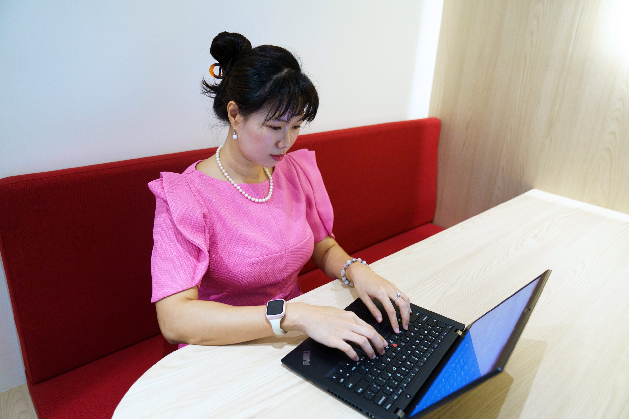 A woman seated at a table, working on her laptop