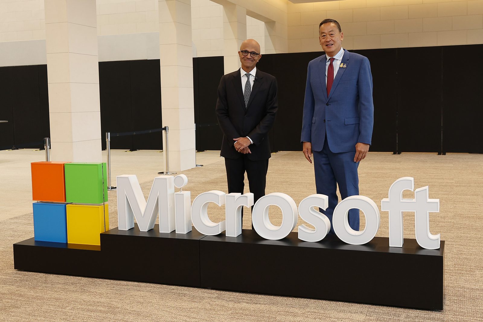 Two men posing behind a Microsoft logo