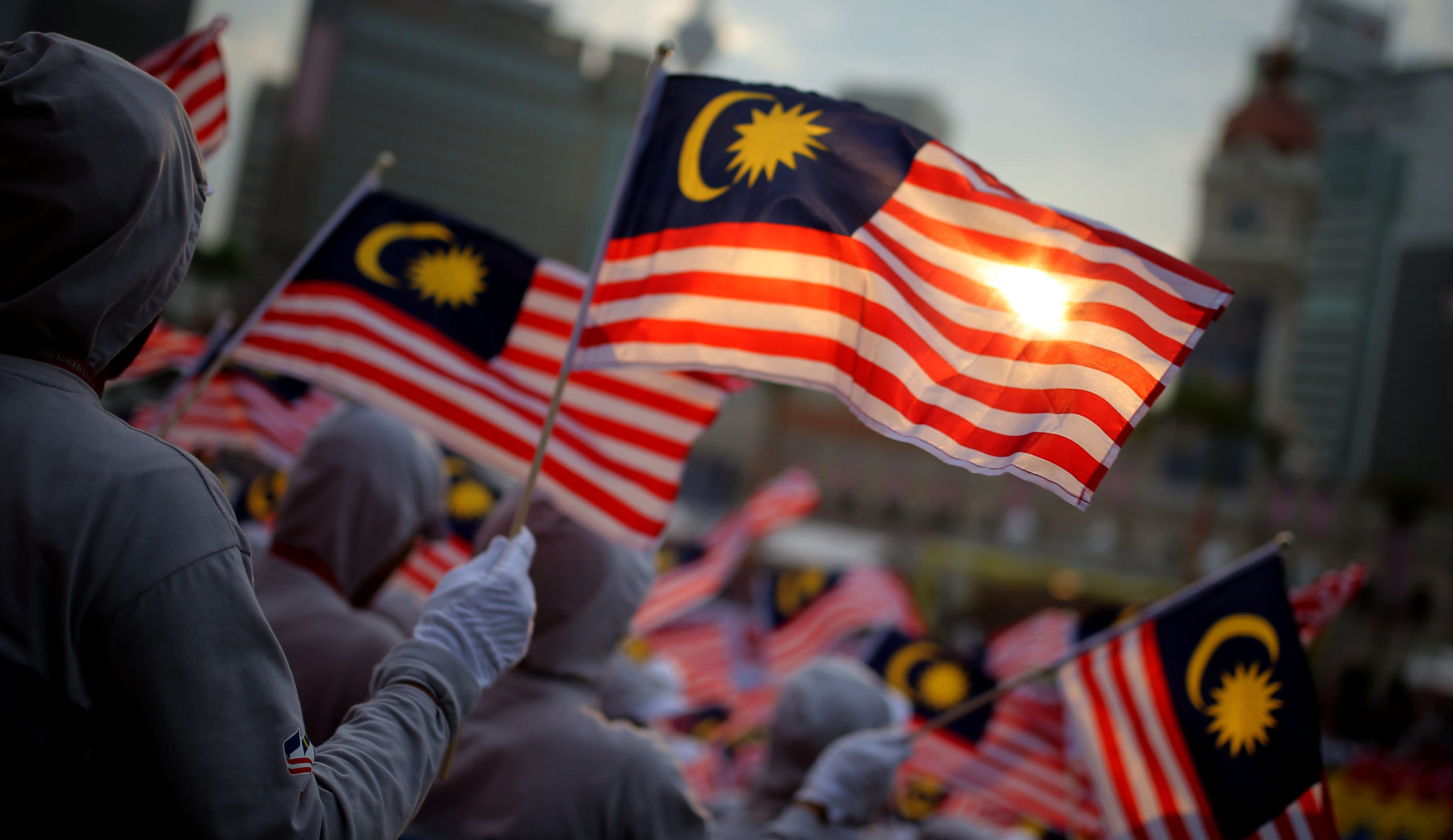People at a Merdeka parade waving the Malaysian flag