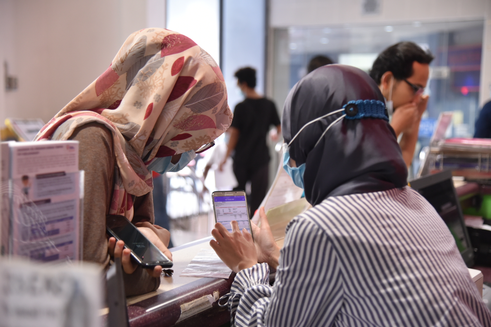 An employee at TNB demonstrating the use of myTNB app to customers.