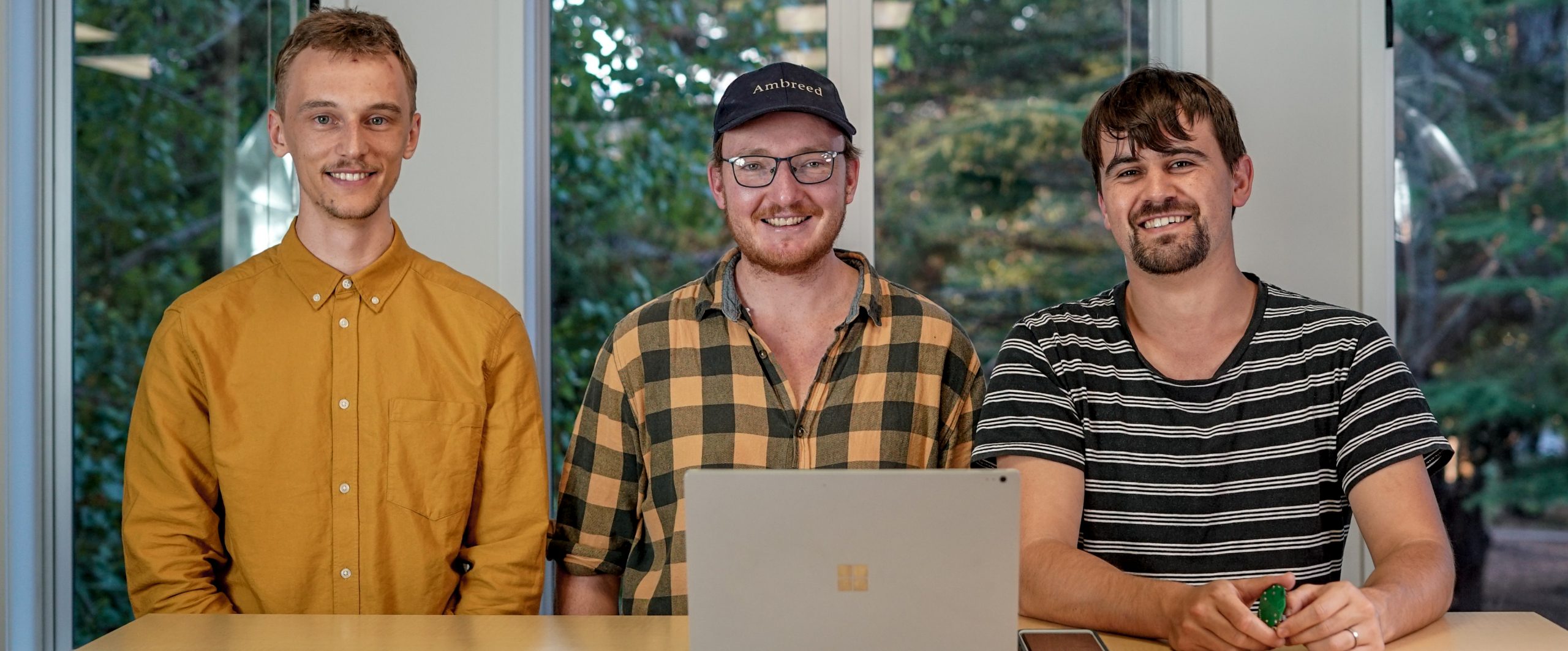 three men standing in front of computer
