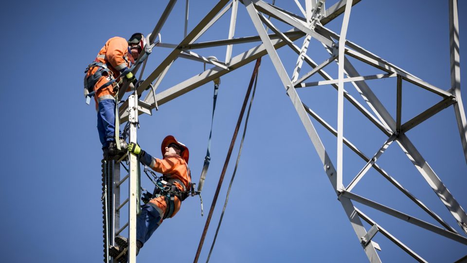 two men climbing electricity structure