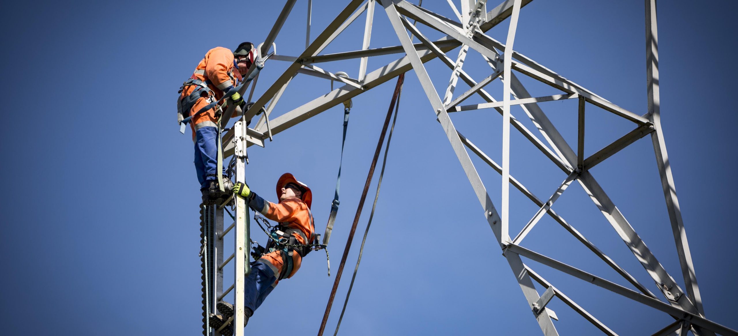 two men climbing electricity structure