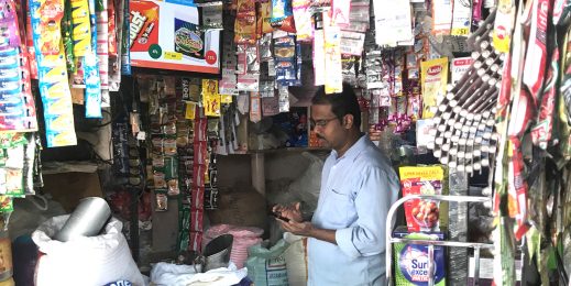 Kirana store owner manages the advertisements on the LED screen in his small store.