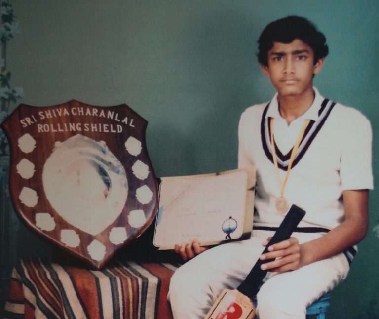 A boy poses with an award shield and cricket bat