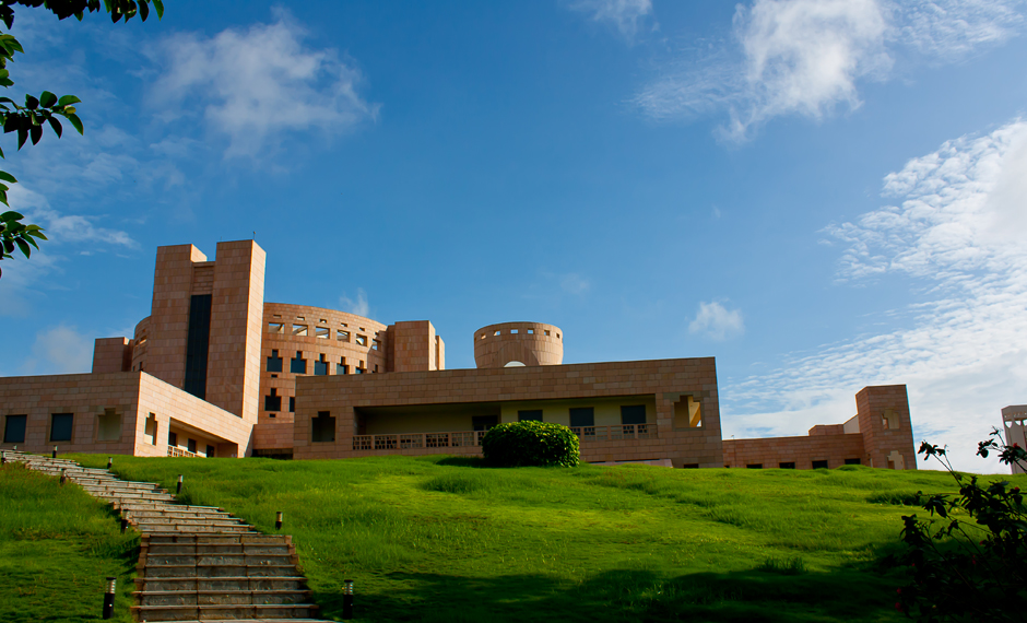 ISB Hyderabad Campus - A building against the backdrop of blue skies and a green lawn in front