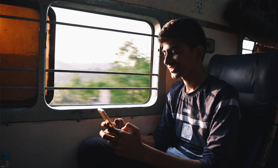 A person sitting in a train operating his mobile
