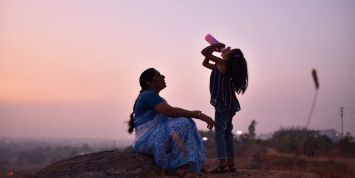 Grandmother and granddaughter drinking water sitting on the hills